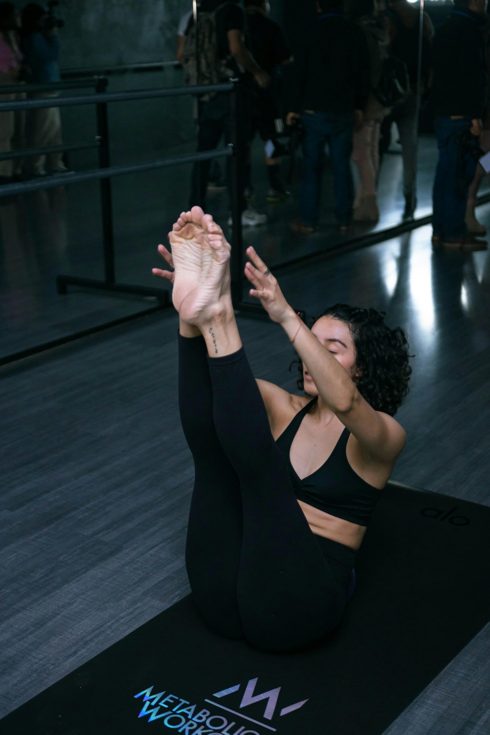 Woman practicing yoga in a modern gym, focusing on flexibility and balance with a seated forward bend pose.